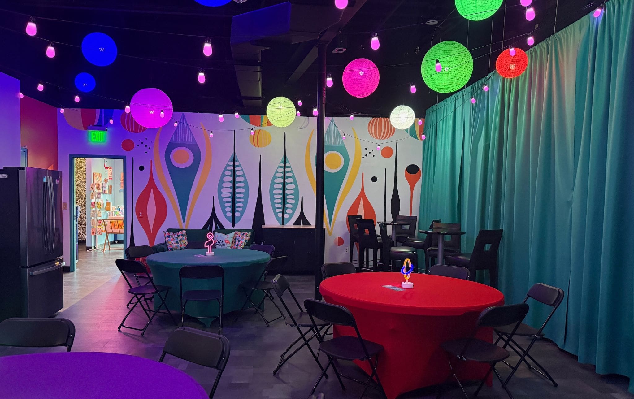 Private party room with colorful tablecloths, abstract wall murals, and vibrant hanging paper lanterns
