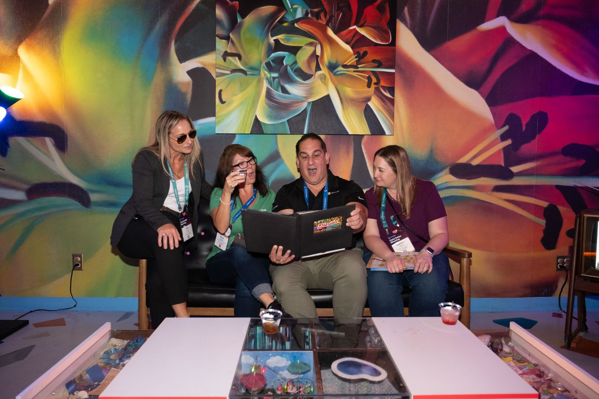Four people look at a binder together in a vibrant, artistic meeting space with colorful floral murals