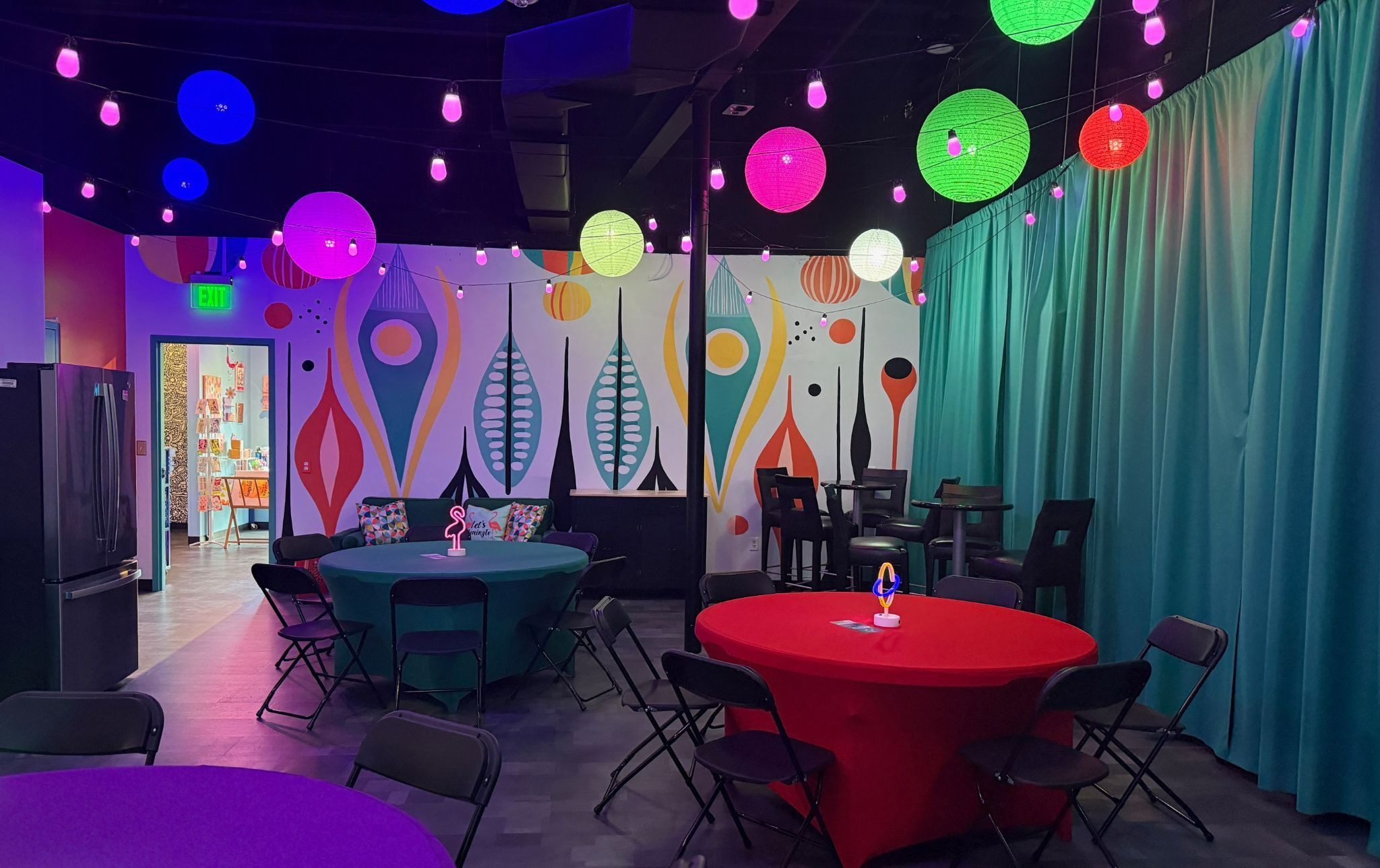 Vibrant meeting space with colorful round tables, abstract wall murals, and glowing paper lanterns