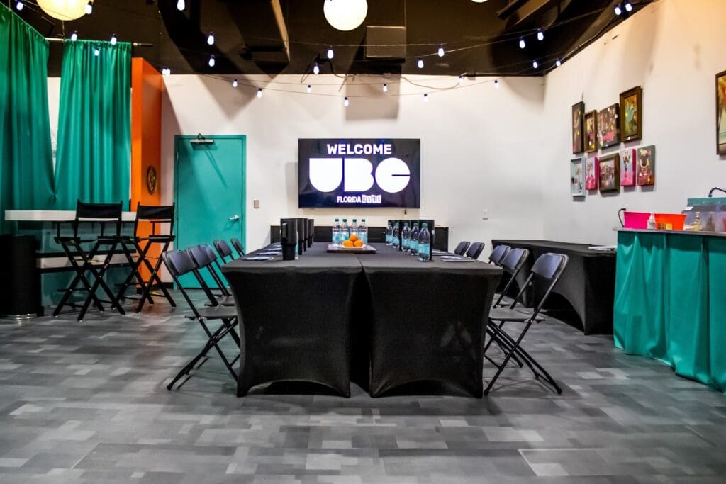 Vibrant meeting room with a long table, string lights, and a screen displaying a welcome message